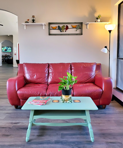 A cozy living room featuring a vibrant red sofa, a mint green coffee table with a potted plant, and warm lighting.