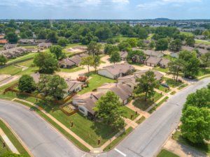 Aerial view of a suburban neighborhood with houses, roads, and lush greenery.