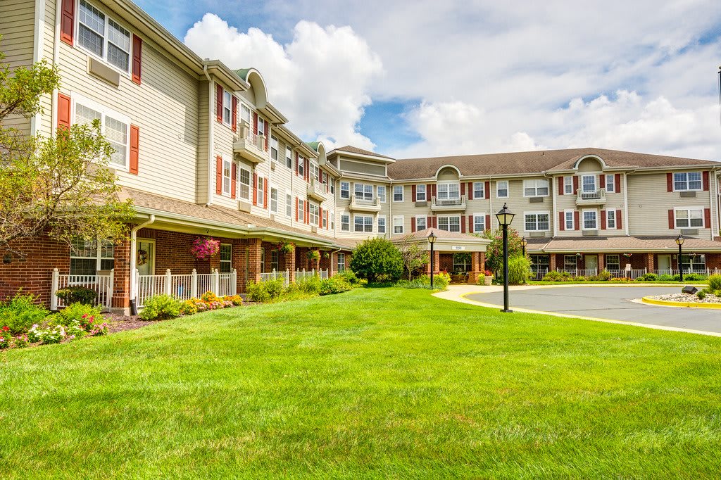 A large residential building with a well-maintained lawn and cloudy sky overhead.