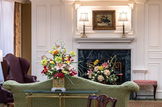 An elegantly decorated living room featuring a cozy fireplace and colorful floral arrangements.