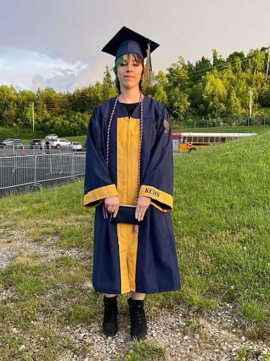 A proud graduate posing in their cap and gown on a sunny day.