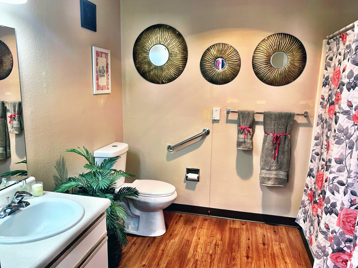 A stylishly decorated bathroom featuring circular mirrors, a toilet, towels on racks, and an indoor plant for added freshness.