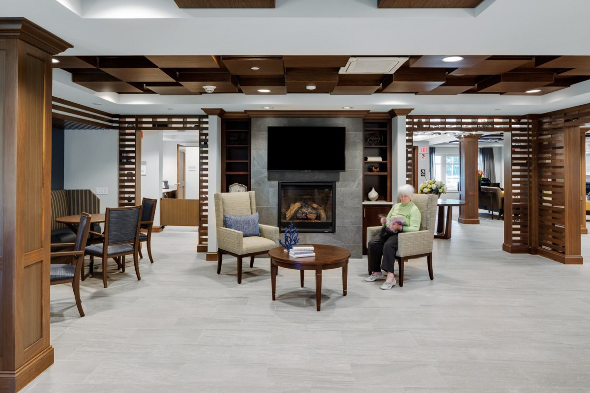 A modern living room with comfortable seating and a fireplace, featuring a TV mounted above.