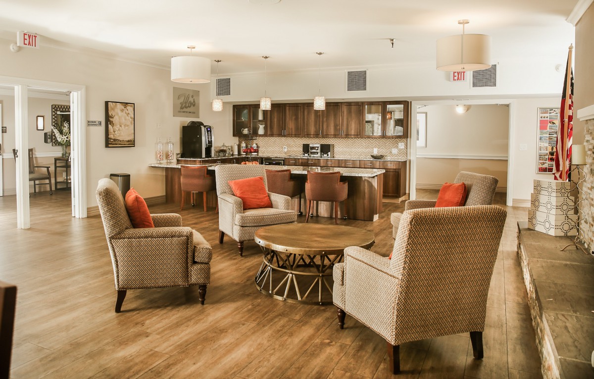 A modern living room with comfortable armchairs, a stylish coffee table, and an open kitchen area featuring wood flooring.