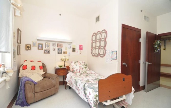 A cozy bedroom with a hospital bed, decorated walls, and a comfortable chair.
