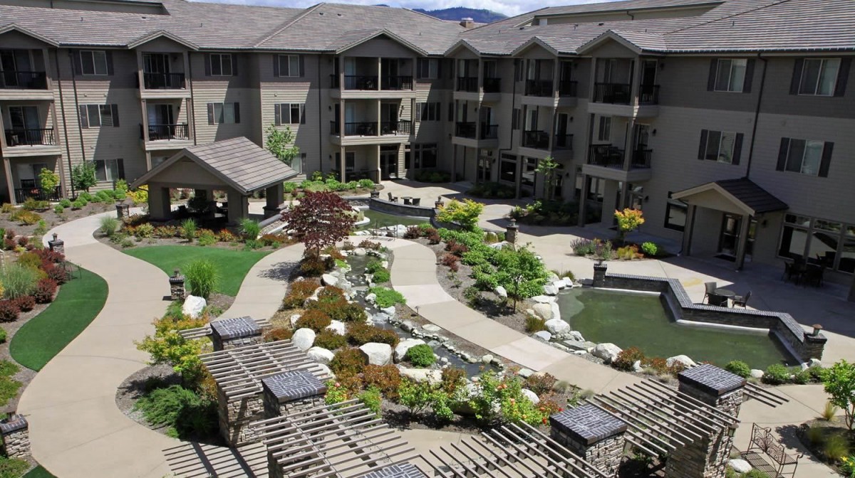A beautifully landscaped courtyard with a pond in the center of a hotel complex.