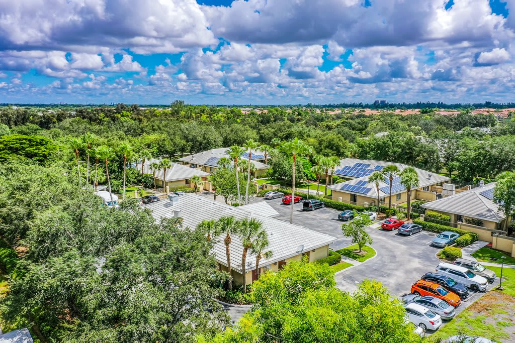 Aerial view of a community surrounded by lush greenery and a cloudy sky.