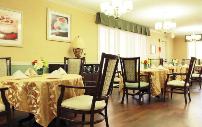 A cozy dining area with elegantly set tables and comfortable chairs, featuring warm lighting and tasteful decor.