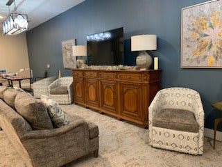 A cozy living room setup with a television on a wooden cabinet, flanked by lamps and surrounded by comfortable seating.