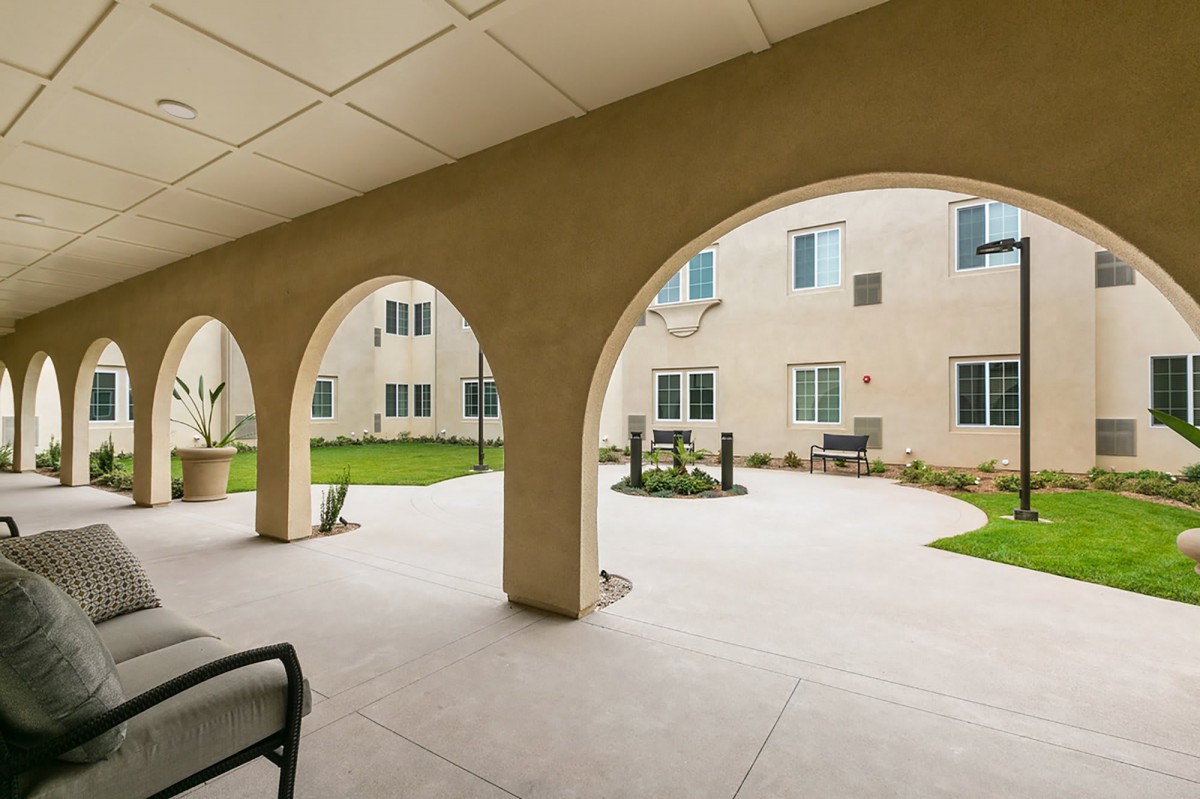 A view of a spacious courtyard with arches overlooking a building exterior.