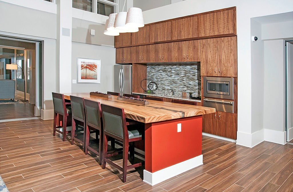 A modern kitchen featuring wooden cabinetry, a large central island with bar stools, and stainless steel appliances.