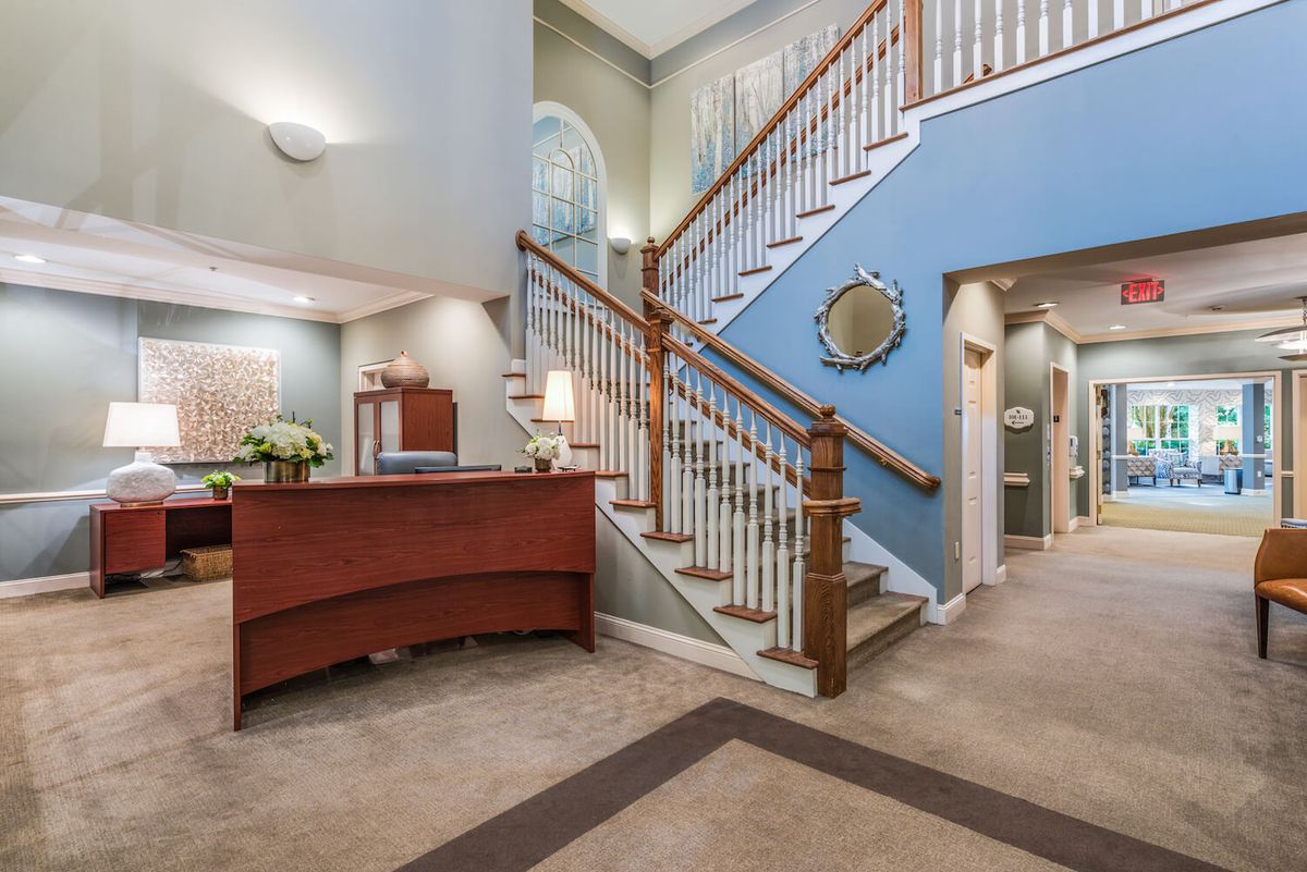 A spacious lobby with a reception desk and a staircase leading to the upper level.