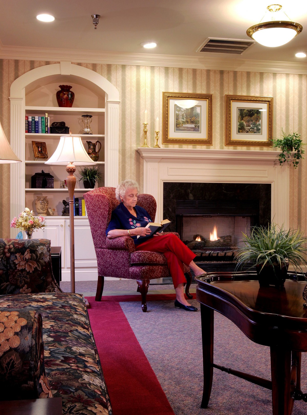 A woman reading a book in a cozy living room by the fireplace.