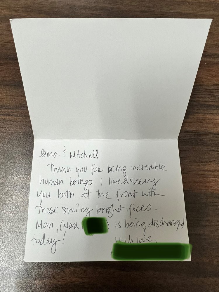 A handwritten note inside a greeting card placed on a wooden surface.