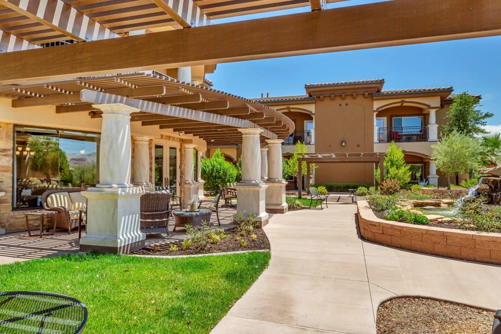 A modern building surrounded by well-maintained gardens and a walkway under a pergola.