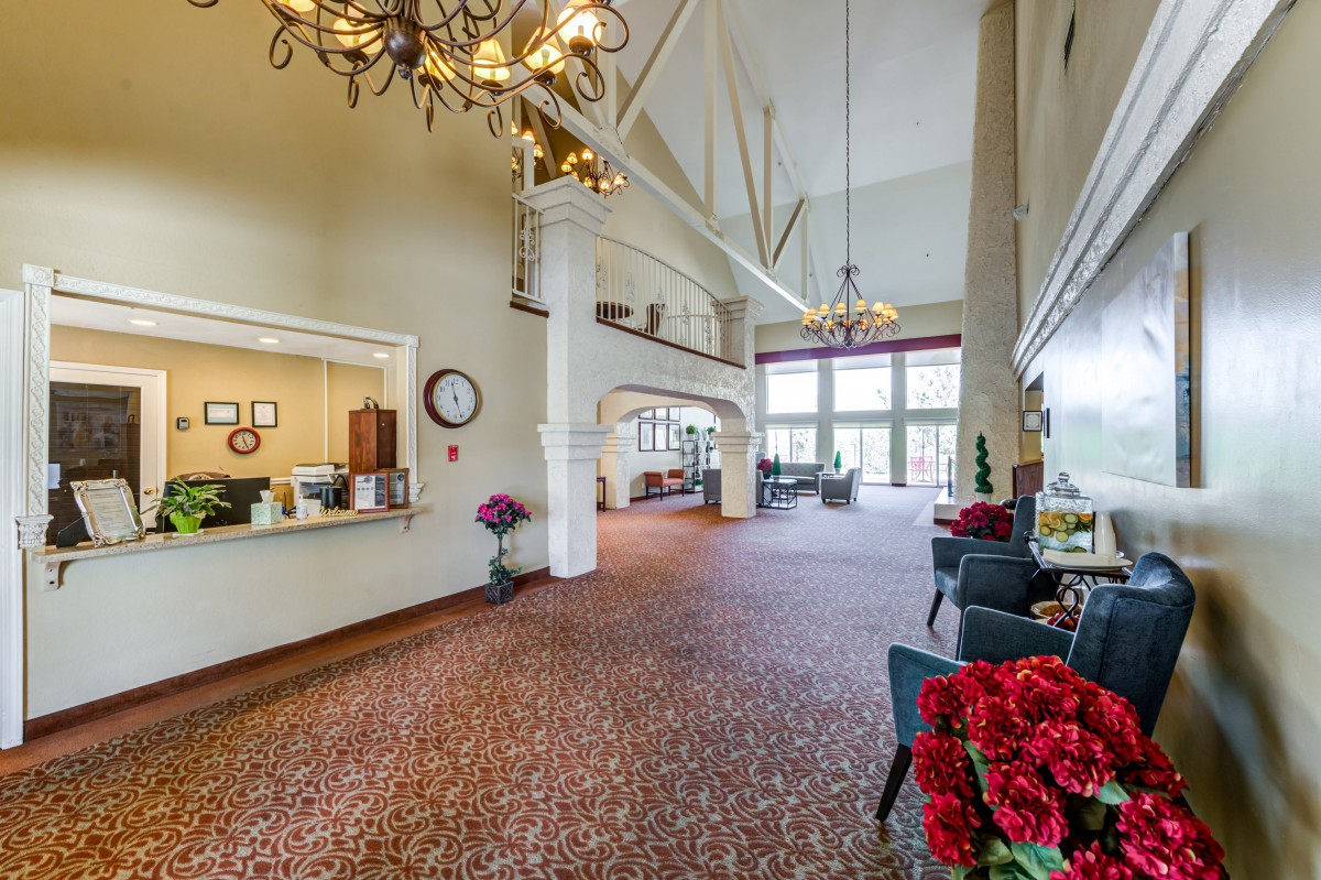 A spacious lobby area featuring chandeliers, a reception desk, and comfortable seating.