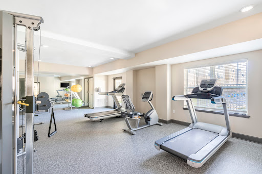 A spacious and well-lit gym area equipped with various exercise machines.