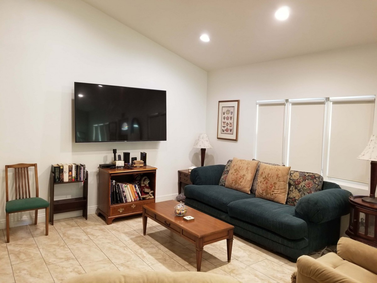 A cozy living room with a sofa, coffee table, and wall-mounted TV.