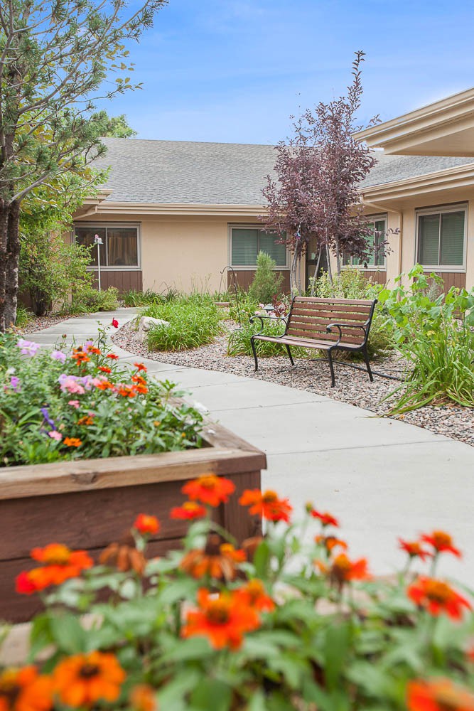 A peaceful garden with a walkway, bench, and vibrant flowers.
