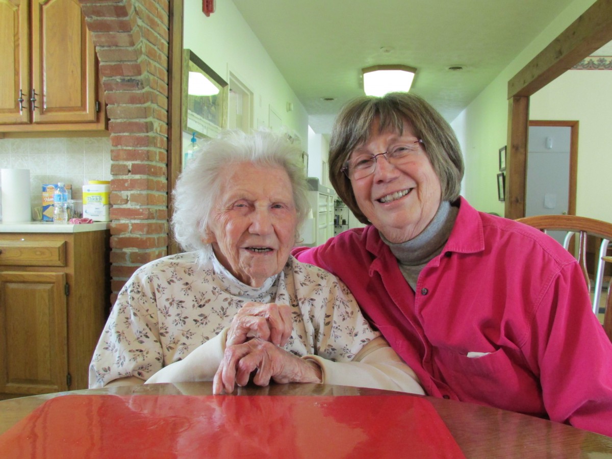 Two elderly women smiling and enjoying each other's company indoors.