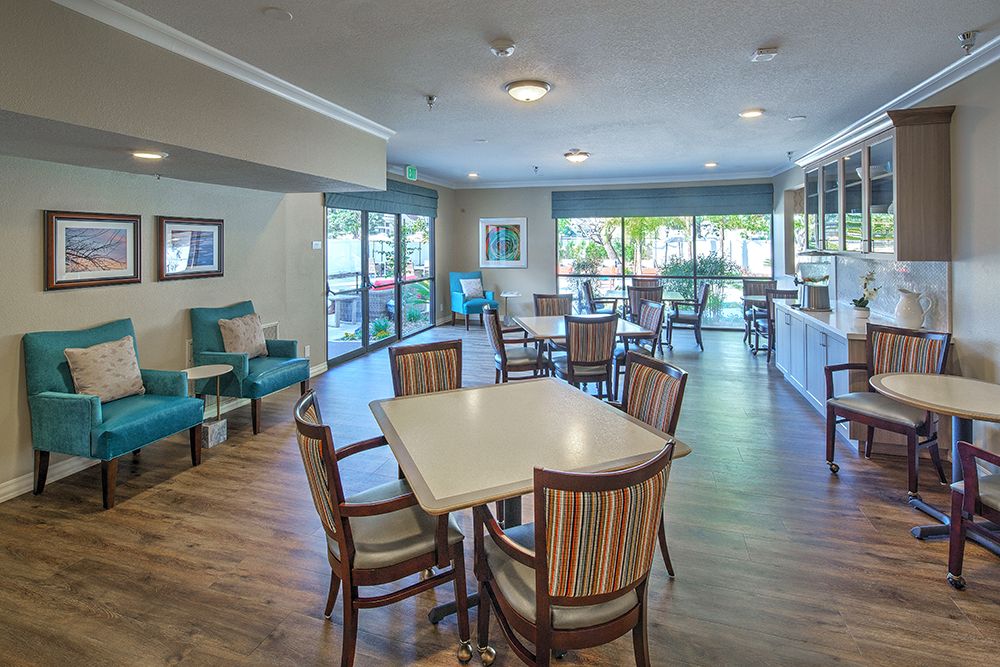 A modern lounge area with dining tables and chairs, featuring large windows and stylish decor.