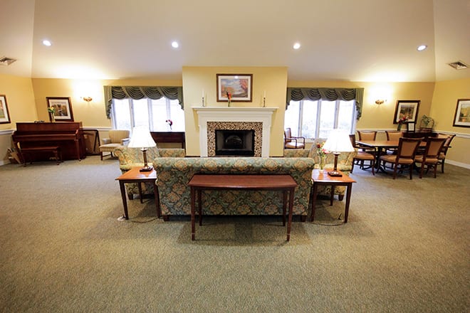 A cozy living room with a central fireplace, surrounded by comfortable seating and warm lighting.