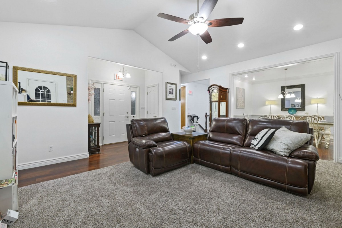 A modern living room featuring a leather sectional sofa, ceiling fan, and elegant decor.