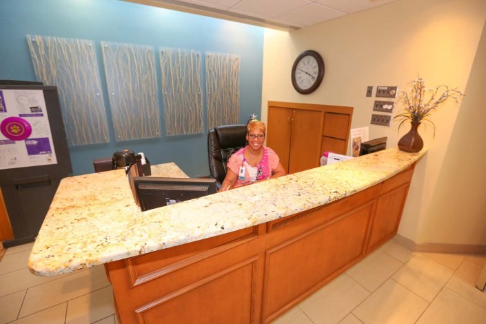 A receptionist seated at an office reception desk in a lobby setting.