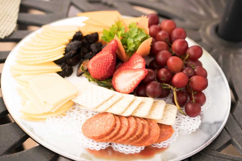 A cheese and fruit platter featuring strawberries, grapes, and sliced meats.