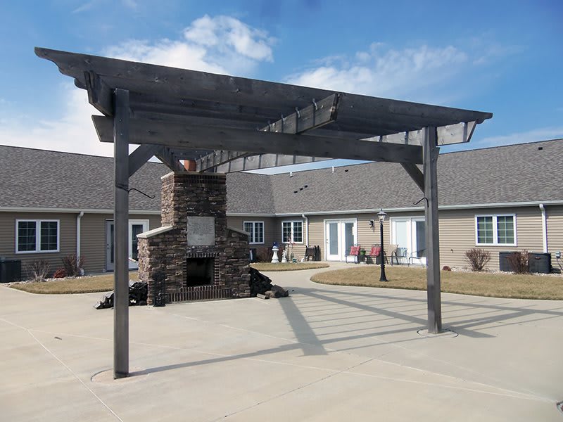 An outdoor pergola with a brick fireplace in a housing complex courtyard.