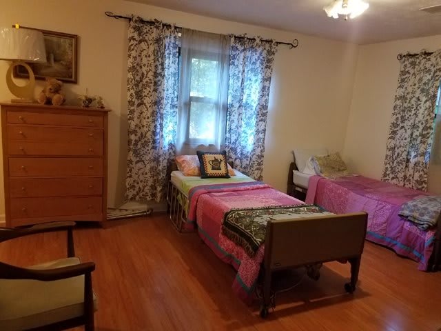 A cozy bedroom with twin beds and a wooden floor.