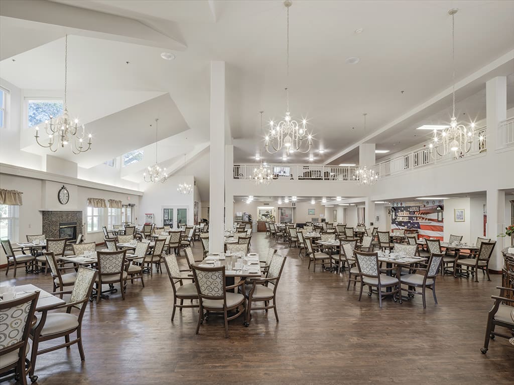 A spacious and elegantly designed dining area with multiple tables, chairs, and chandeliers.