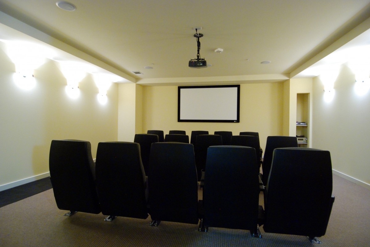 An empty home theater room with rows of seats and a projection screen.