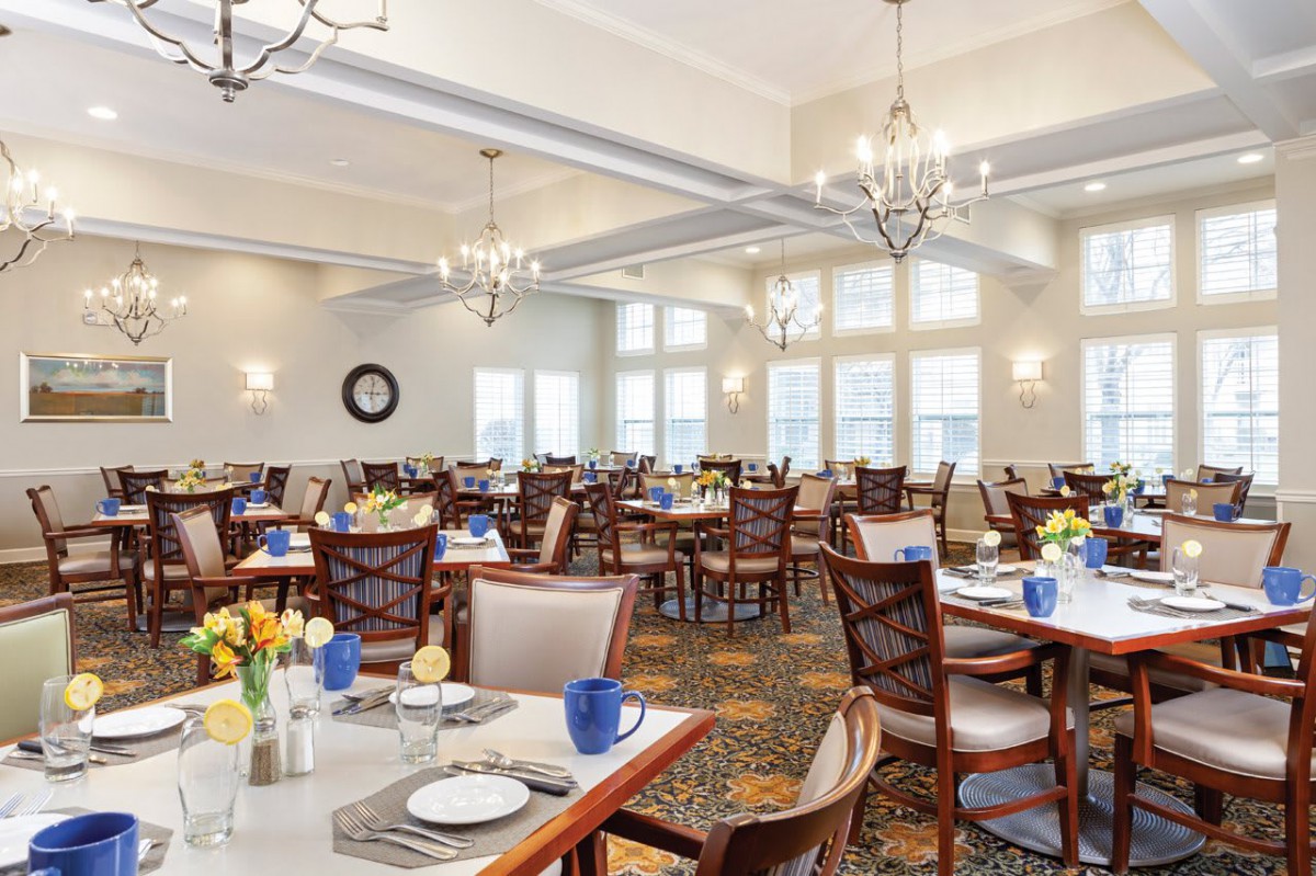 A spacious dining room with elegantly set tables and chandeliers.