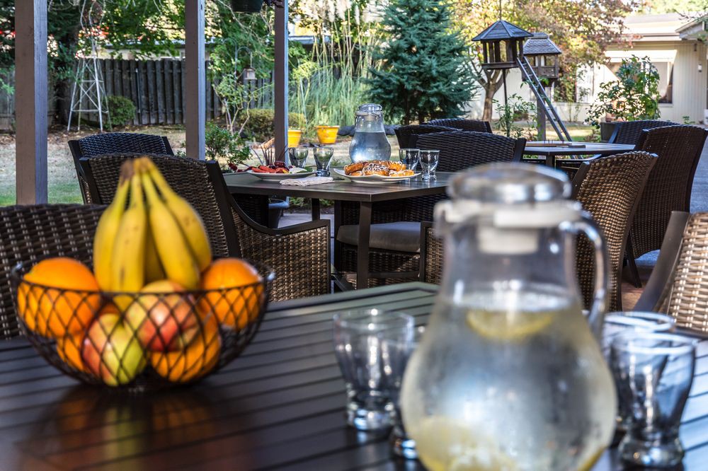 A cozy outdoor dining setting with a fruit basket and a pitcher of lemon water on the table.