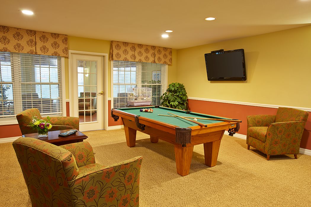 A cozy game room featuring a pool table, comfortable seating, and a wall-mounted TV.