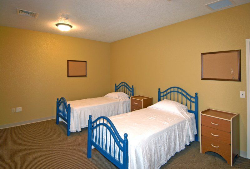 A simple bedroom with two twin beds and minimal decor.