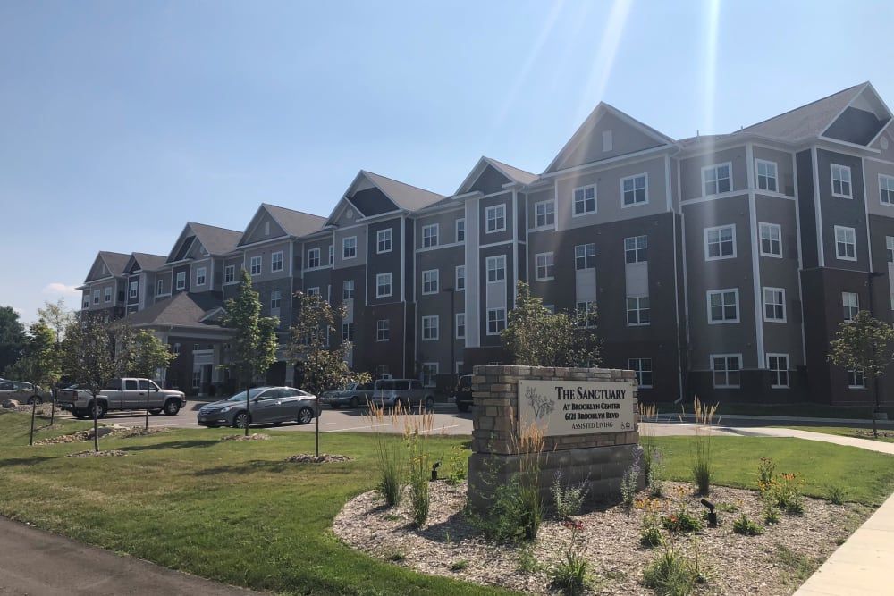 A residential apartment complex with a parking lot and a landscaped garden in front.