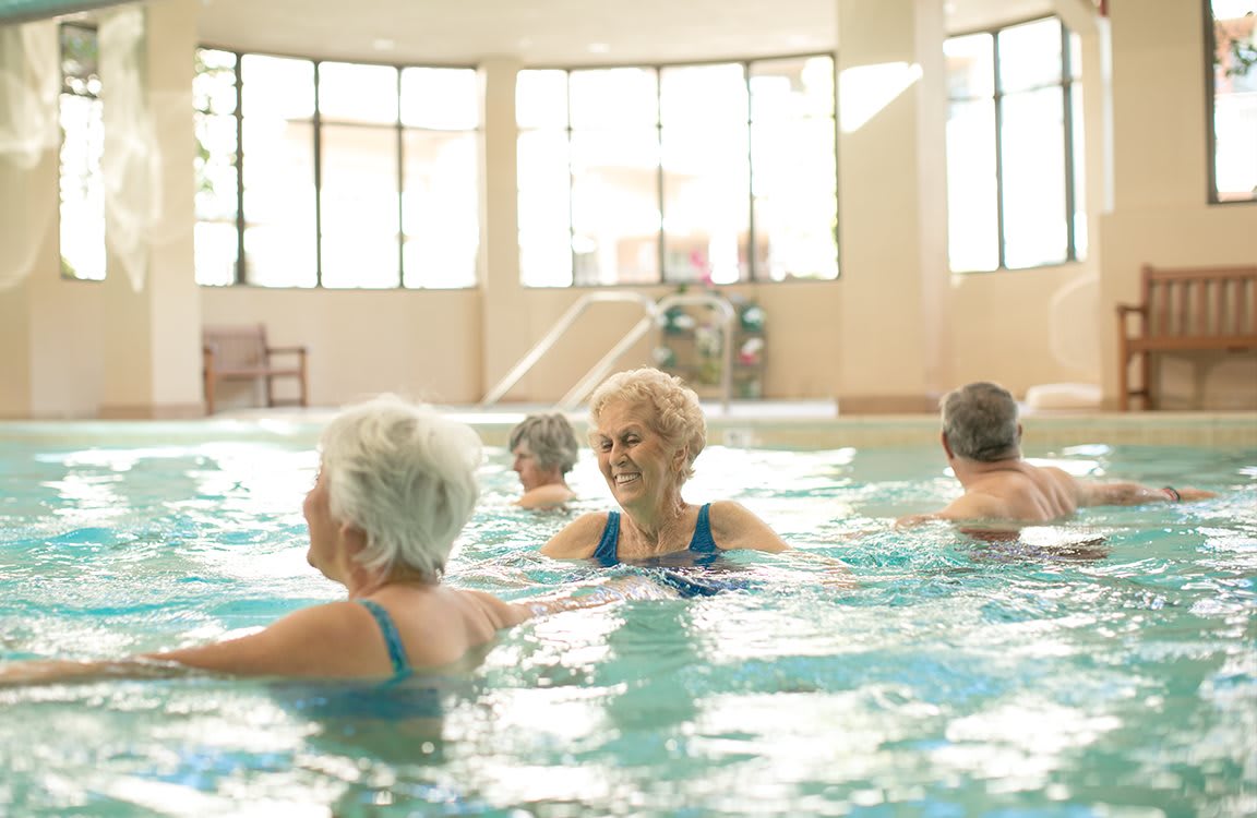 Elderly individuals participating in a water exercise session at an indoor pool.