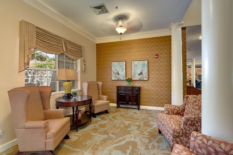 A cozy living room with comfortable armchairs, artwork on the wall, and soft lighting.