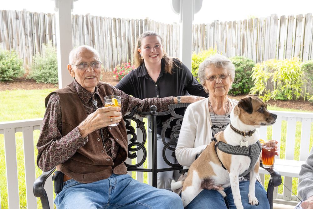 A family moment with an elderly couple and their dog seated on a bench.