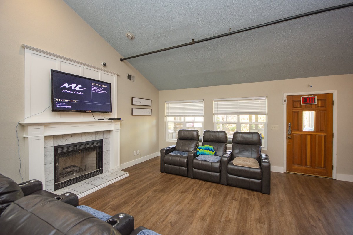 A cozy living room with a home theater setup, featuring recliner chairs and a fireplace.