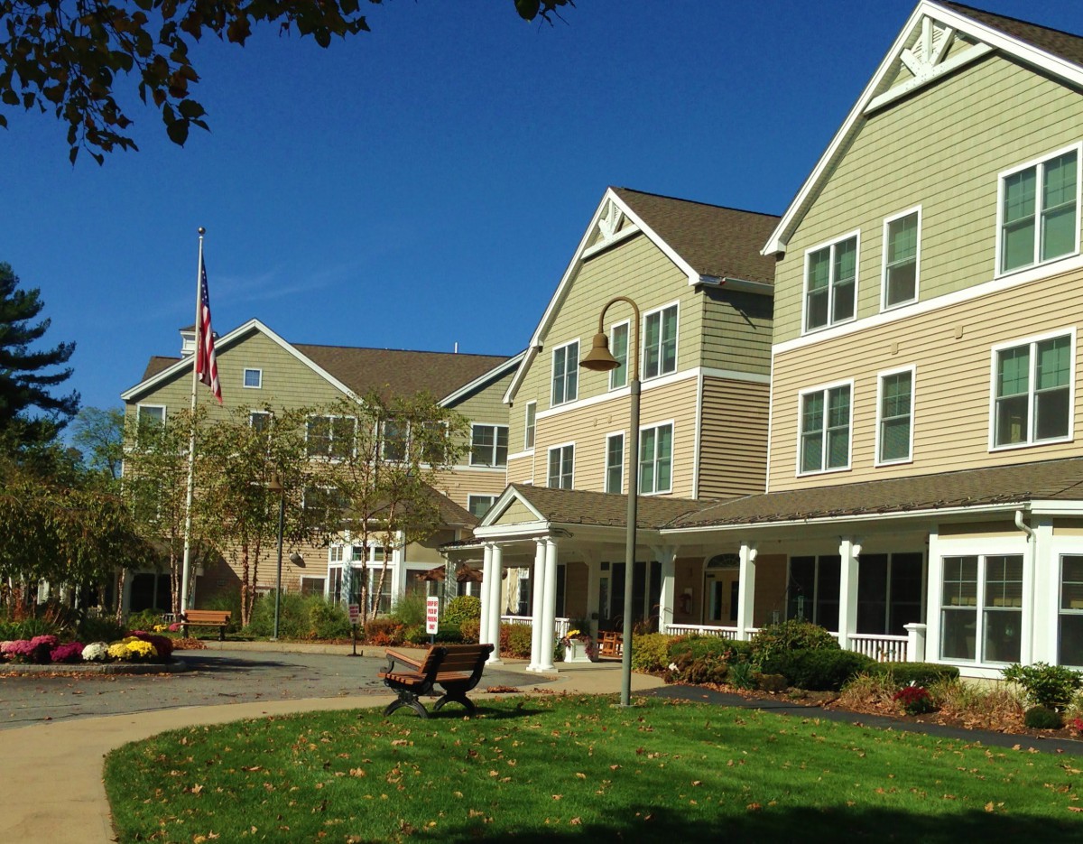 A large residential building with a landscaped lawn and pathway on a clear day.