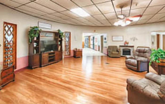A spacious living room with hardwood flooring, featuring a television, comfortable seating, and a fireplace.