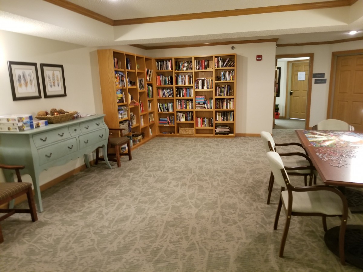 A small library room with bookshelves, seating, and a table.