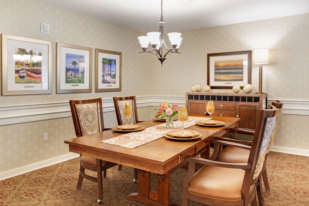 A neatly arranged dining room featuring a wooden table, chairs, and wall art.