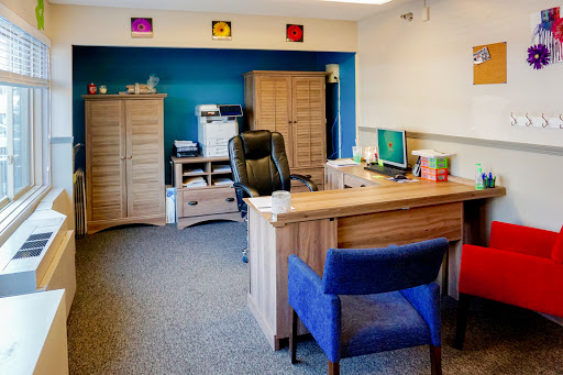 A modern office setup featuring a wooden desk, ergonomic chair, and colorful wall accents.