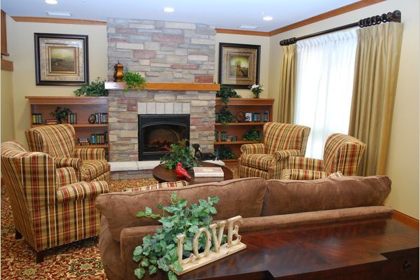 A cozy living room featuring a stone fireplace, comfortable armchairs, and a decorative 'LOVE' sign.