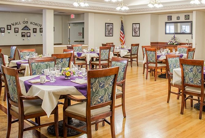 A well-decorated dining room with round tables and chairs, featuring an American flag in the background.