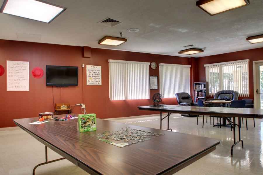 A community center activity room with tables, chairs, and a puzzle in progress.